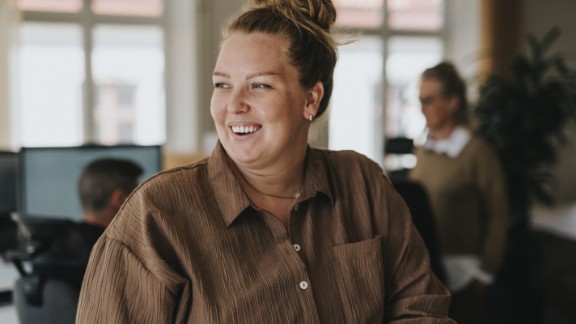 En kvinde i brun skjorte griner