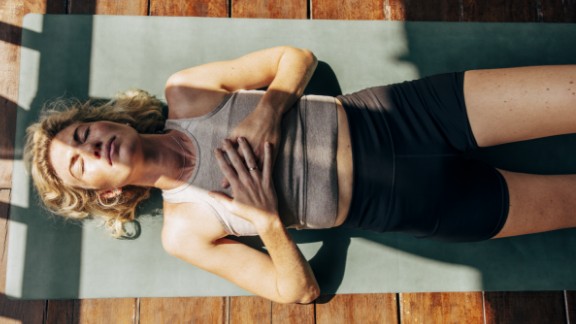 Kvinde ligger på yogamåtte