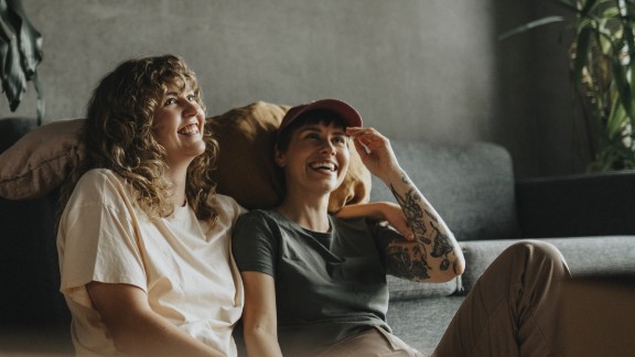 Et par kvindelige kærester sidder foran deres sofa