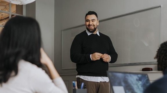 Mandlig lærer smiler til gymnasieklasse