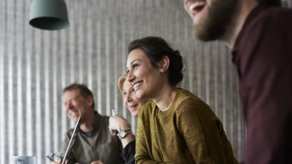 Kvinde_griner_blandt_andre_text-image-50_50_576x324