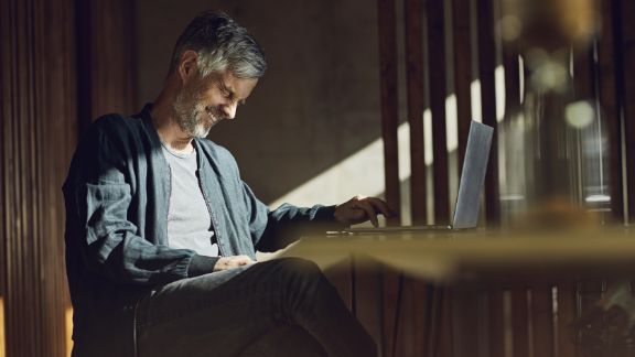 Mand_griner_ved_skrivebord_text-image-50_50_576x324