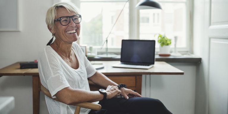 Kvinde_griner_ved_skrievbord_content-header_768x384