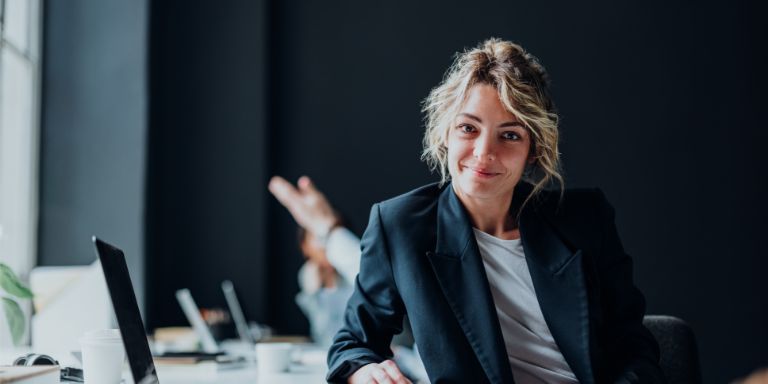 Kvinde_smiler_ved_skrivebord_computer_content-header_768x384